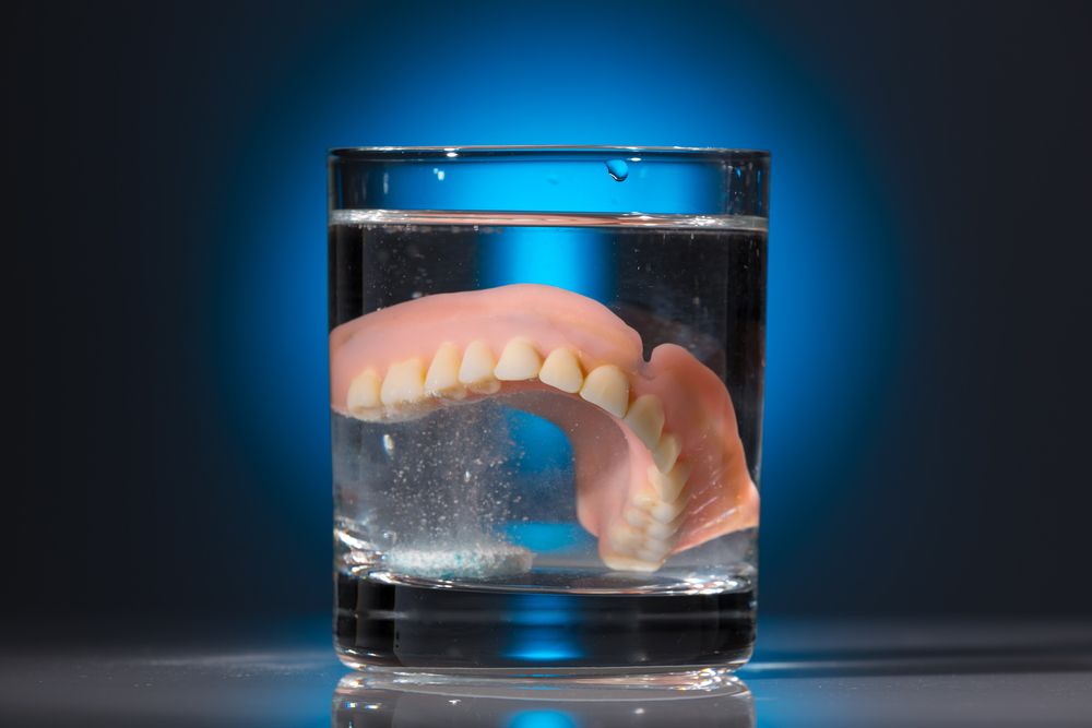 Dentures in glass of cleaning solution